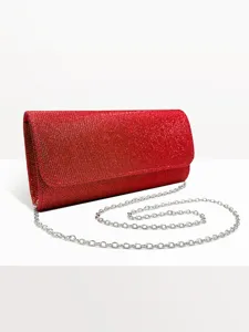 Red glitter clutch bag detail shot showing sparkling fabric and silver chain strap texture.