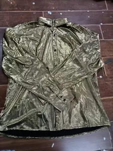 Shiny metallic texture detail of the gold long sleeve shirt showing the fabric and button finish.