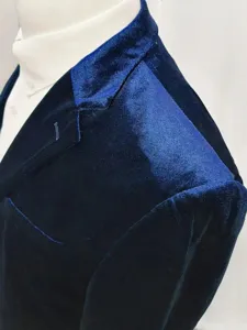 Close-up detail of dark blue velvet suit jacket shoulder and lapel, premium fabric texture.