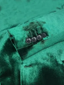 Detailed close-up of a men's green velvet suit sleeve cuff featuring four elegant black buttons.