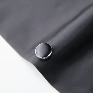 Detailed close-up of a stylish black suit button with silver trim on dark fabric.