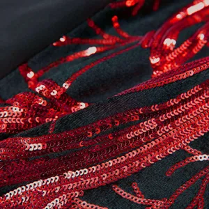 Detailed shot of boys suit fabric featuring shiny red sequin branch embroidery on black velvet.