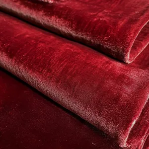 Close-up of wine red velvet fabric showing soft texture, rich color and subtle sheen detail.