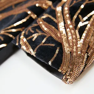 Close-up detail of luxury boys black velvet jacket with gold sequin branch embroidery.
