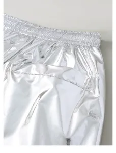 Close-up detail of shiny metallic silver pants waistband, elastic design, shiny fabric.