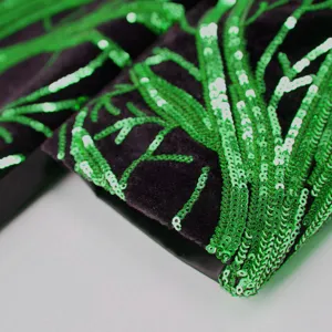 Detailed shot of boys suit jacket with green sequin embroidery on black fabric, stylish.