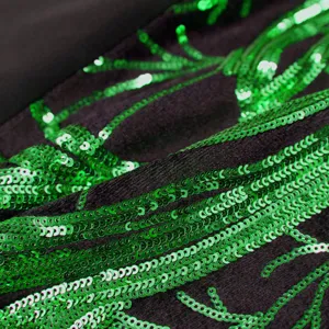 Close up of green sequin branch embroidery on black fabric detailed garment material showcase