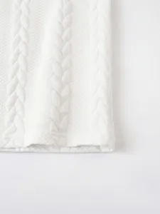 Close-up detail shot of white knitted waffle jacquard fabric featuring classic cable texture.