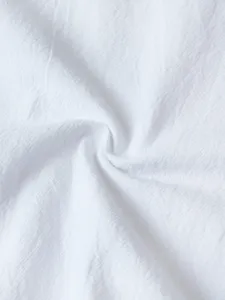 Close-up of white textured cotton fabric, showing fine weave, soft handfeel and natural wrinkles.
