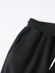Primo piano di pantaloni felpati neri, vita elastica, tessuto morbido, abbigliamento casual invernale.