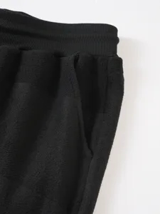 Vista dettagliata dei pantaloni felpati da uomo in nero solido con tasca e vita elasticizzata.