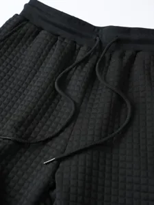 Black waffle knit casual pants detail, elastic drawstring waistband, comfortable fit.
