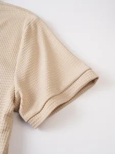 Waffle knit fabric short sleeve detail, soft texture and breathable summer mens top close up.