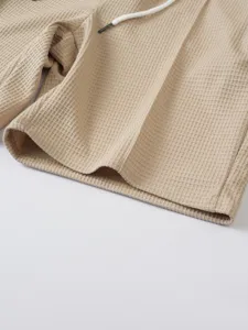 Detailed view of men's waffle knit casual shorts fabric in khaki with a white cord.