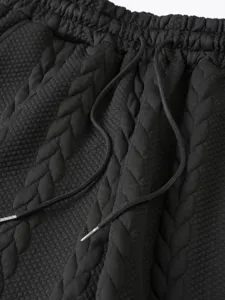 Close-up of black textured knit fabric with elastic waistband and adjustable drawstring details.