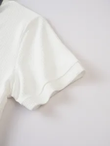 Detailed close-up view of white waffle knit short sleeve fabric texture and cuff design.