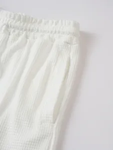 Detailed view of men's white waffle texture apparel elastic waistband and pocket design.