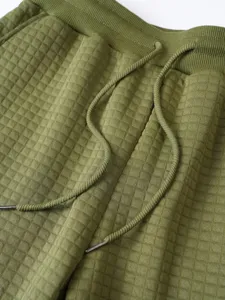 Green waffle knit sweatpants detail shot showing elastic waistband and metal tipped drawstrings.