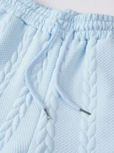 Close-up detail of light blue textured casual shorts waistband with braided pattern drawstrings.