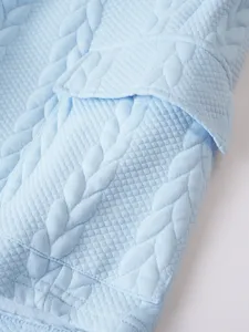 Detailed close-up view of light blue textured fabric showcasing the garment's unique design.