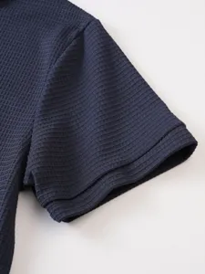 Detail shot of the dark navy blue waffle knit polo shirt short sleeve cuff texture.