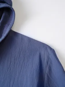 Détail de chemise à capuche en lin et coton bleu, vue rapprochée des coutures.