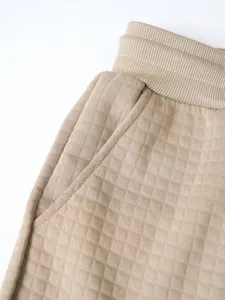 Detail close-up of men's waffle knit casual pants waist and pocket, khaki textured fabric.