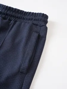 Navy blue waffle knit men's shorts waist and pocket detail shot, premium fabric texture.