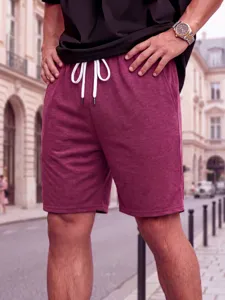 Detail view of men's casual burgundy drawstring shorts, comfortable loose fit for summer sports.
