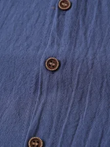 Gros plan sur la texture du tissu bleu et les details des boutons marron foncé de chemise