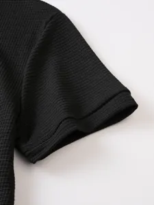 Detailed shot of mens black waffle knit polo shirt short sleeve cuff showing textured fabric.