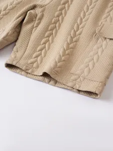 Detailed shot of men's casual knitted jacquard fabric shorts in khaki with cable knit texture.