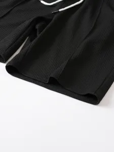 Black waffle knit casual shorts detail close-up showing soft textured fabric and white drawstring.