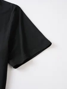 Dettaglio in primo piano del polsino della t-shirt nera, tessuto e cuciture pulite.