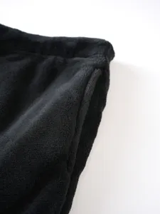 Close-up detail of black coral fleece pants, showing soft texture and elastic waist.