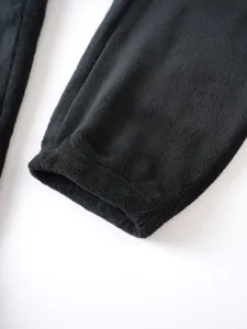 Detailed view of men's black fleece pants cuff, cozy winter thermal fabric texture.