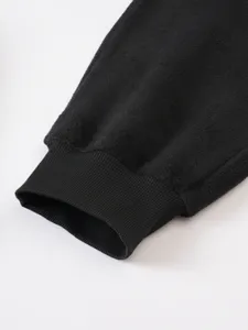 Primo piano dettaglio di pantaloni felpati neri con polsino a coste e spessa texture.