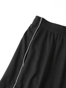 Dettaglio pantaloncini sportivi a rete nera da uomo con vita elastica e tasca zip.