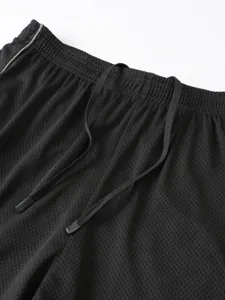 Vista di dettaglio pantaloncini sportivi fitness uomo, tessuto a rete traspirante elast.