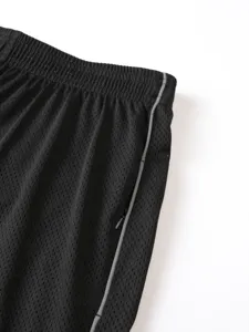 Primo piano dei dettagli di pantaloncini sportivi a rete da uomo, tessuto traspirante e tasca zip.