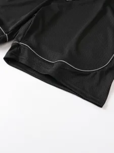 Dettaglio ravvicinato di pantaloncini sportivi da uomo in rete nera con bordatura.