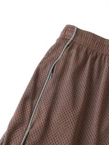 Primo piano sui dettagli dei pantaloncini sportivi marroni in rete con tasca con cerniera.