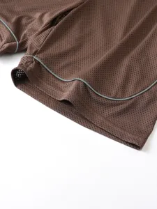Primo piano dettagliato di pantaloncini sportivi marroni in rete con rifinitura catarifrangente grigia.