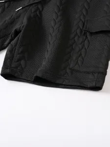Close-up detail of black men's textured jacquard knit shorts with cable pattern and drawstring.