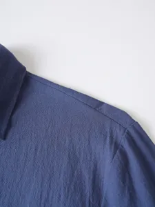 Close-up detail view of mens solid blue long sleeve casual shirt shoulder and collar