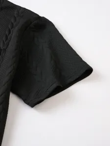 Close-up detail of black knit waffle textured short sleeve, highlighting fabric weave and quality.