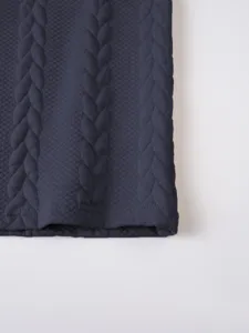 Close-up detailed view of the dark blue knitted waffle jacquard fabric texture and hem line.