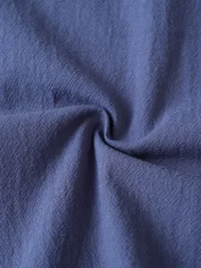 Close up of dark blue textured fabric showing fine weave and soft drape for casual shirts.