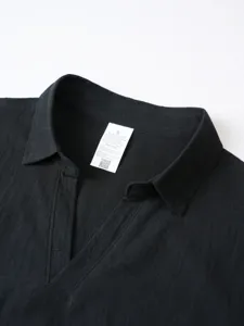 Men's solid black linen blend shirt collar detail close-up view showing care label tag.