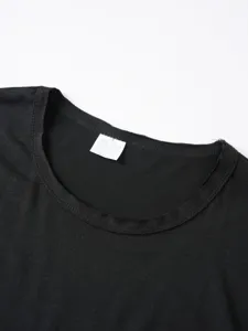 Primo piano dei dettagli del collo della maglietta nera con etichetta di taglia e cura.